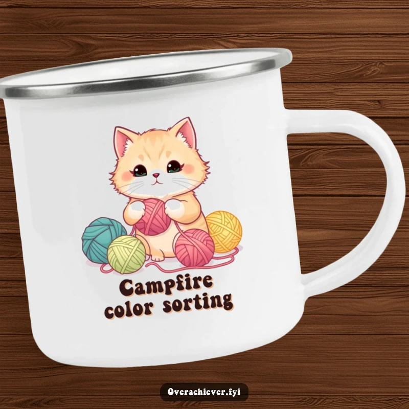 Funny fluffy cat meticulously organizing yarn balls by color gradient on a camping mug, adding humor to outdoor crafting.